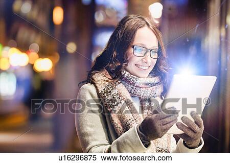 Portrait of young attractive woman smiling and using digital tablet while on night shopping View Large Photo Image Stock Photography - Portrait of young attractive woman smiling and using digital tablet while on night shopping. Fotosearch