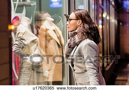 Portrait of young attractive woman looking at the dress on a manequin in shop through the window View Large Photo Image Stock Photography - Portrait of young attractive woman looking at the dress on a manequin in shop through the window. Fotosearch