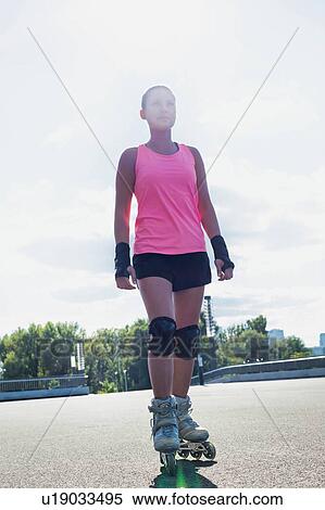 Stock Photography - Portrait of young attractive woman wearing rollerblades. Fotosearch