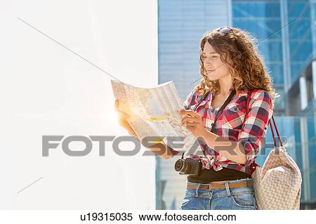 Portrait of young attractive woman looking on the map in the city with lens flare in background View Large Photo Image Stock Photography - Portrait of young attractive woman looking on the map in the city with lens flare in background. Fotosearch