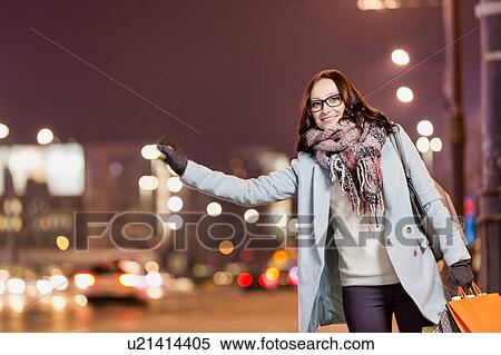 Portrait of young attractive woman standing while calling for taxi after night shopping View Large Photo Image Stock Photography - Portrait of young attractive woman standing while calling for taxi after night shopping. Fotosearch