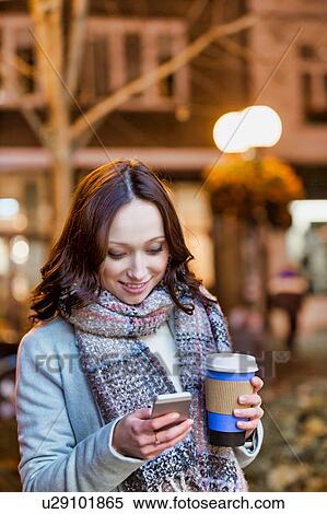 Portrait of young attractive woman holding cup of coffee while using smartphone View Large Photo Image Stock Photography - Portrait of young attractive woman holding cup of coffee while using smartphone . Fotosearch
