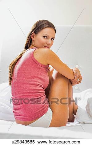 Stock Photography - Portrait of young attractive woman sitting in bed with her underwear . Fotosearch