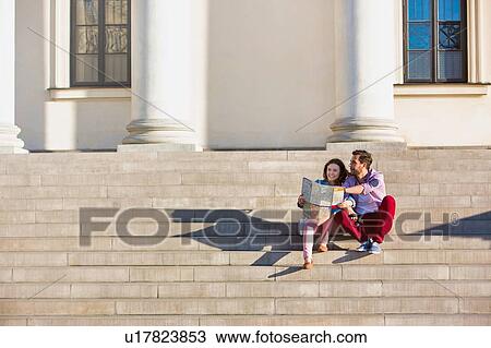Stock Image - Portrait of young attractivec couple sitting while looking on the map. Fotosearch