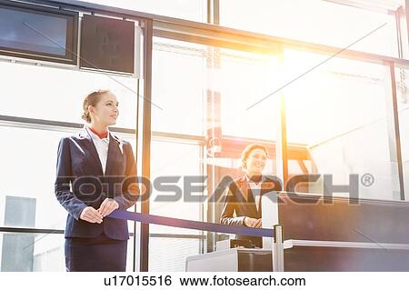 Stock Photograph - Portrait of young beautiful airport staff opening the gate for boarding in airport . Fotosearch
