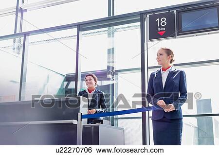 Stock Photograph - Portrait of young beautiful airport staff opening the gate for boarding in airport . Fotosearch
