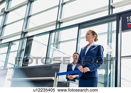 Stock Photography - Portrait of young beautiful airport staff opening the gate for boarding in airport . Fotosearch