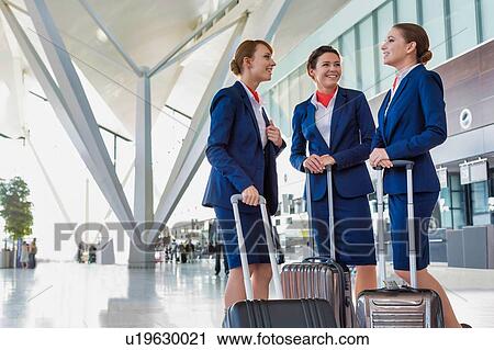 Stock Image - Portrait of young beautiful confident flight attendants talking in airport. Fotosearch