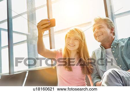 Portrait of young beautiful teenage girl taking selfie with her father in airport View Large Photo Image Stock Image - Portrait of young beautiful teenage girl taking selfie with her father in airport. Fotosearch