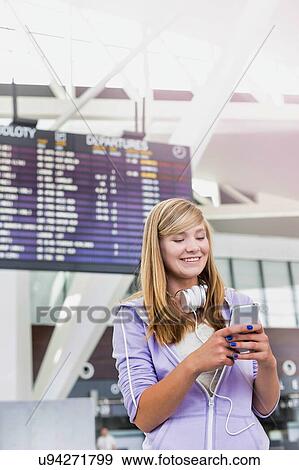 Portrait of young beautiful teenage girl using smartphone in airport with lens flare View Large Photo Image Stock Photo - Portrait of young beautiful teenage girl using smartphone in airport with lens flare. Fotosearch