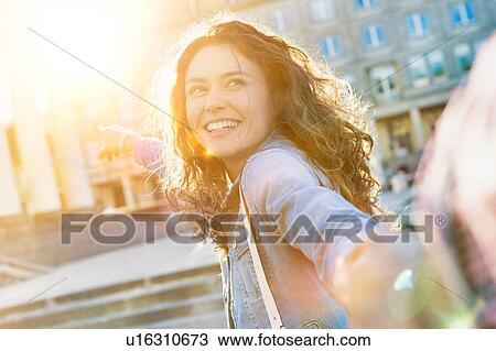 Portrait of young beautiful woman posing while being photograph by his boyfriend with lens flare in background View Large Photo Image Stock Image - Portrait of young beautiful woman posing while being photograph by his boyfriend with lens flare in background. Fotosearch