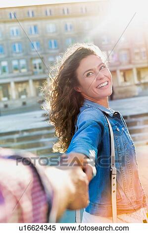 Portrait of young beautiful woman smiling and walking while holding her boyfriend hand View Large Photo Image Stock Photography - Portrait of young beautiful woman smiling and walking while holding her boyfriend hand . Fotosearch