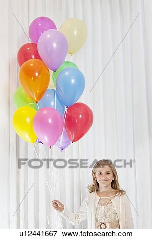Portrait of young birthday girl standing with party balloons View Large Photo Image Stock Photo - Portrait of young birthday girl standing with party balloons. Fotosearch