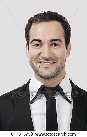 Stock Image - Portrait of young Caucasian businessman smiling against white background. Fotosearch