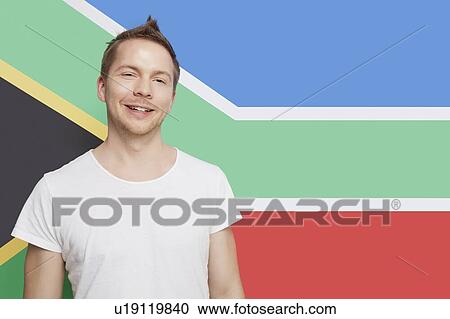Stock Image - Portrait of young Caucasian man smiling against South African flag. Fotosearch