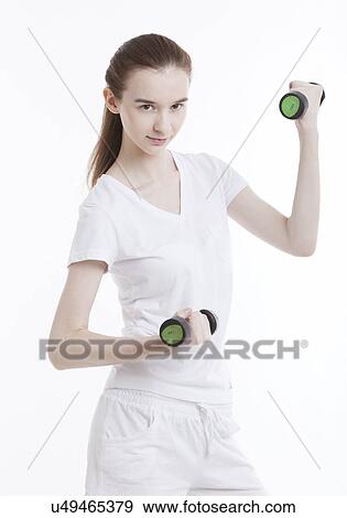 Stock Photo - Portrait of young Caucasian woman exercising with dumbbells against white background. Fotosearch
