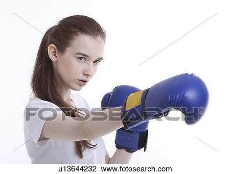 Stock Image - Portrait of young Caucasian woman with boxing gloves against white background. Fotosearch