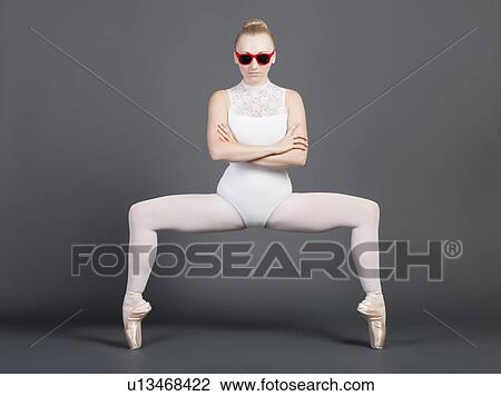 Stock Image - Portrait of young female ballet dancer tiptoeing over grey background. Fotosearch
