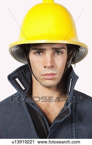 Stock Image - Portrait of young fireman against gray background. Fotosearch