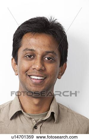 Stock Photo - Portrait of young Indian man smiling against white background. Fotosearch