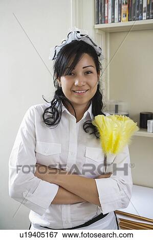 Stock Photo - Portrait of young maidservant holding feather duster. Fotosearch