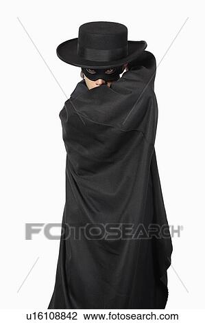 Stock Image - Portrait of young man dressed as Zorro over gray background. Fotosearch