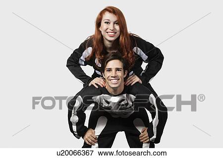 Portrait of young man giving piggyback ride in skeleton costume over gray background View Large Photo Image Stock Photo - Portrait of young man giving piggyback ride in skeleton costume over gray background. Fotosearch