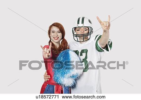 Portrait of young man in football uniform and cheerleader gesturing over gray background View Large Photo Image Stock Image - Portrait of young man in football uniform and cheerleader gesturing over gray background. Fotosearch