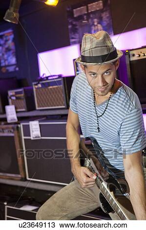 Portrait of young man playing electric guitar in music store View Large Photo Image Stock Image - Portrait of young man playing electric guitar in music store. Fotosearch