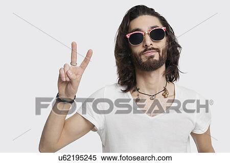 Portrait of young man wearing sunglasses gestures peace sign against white background View Large Photo Image Stock Photography - Portrait of young man wearing sunglasses gestures peace sign against white background. Fotosearch