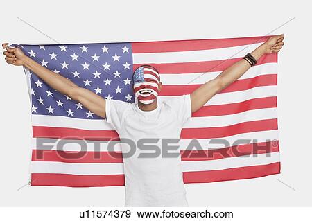 Stock Photo - Portrait of Young man with American flag and painted face against white background. Fotosearch