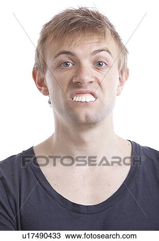 Stock Image - Portrait of young man with fake teeth against white background. Fotosearch