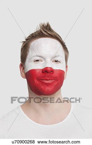 Stock Photo - Portrait of young man with Polish flag painted on face smiling against white background. Fotosearch