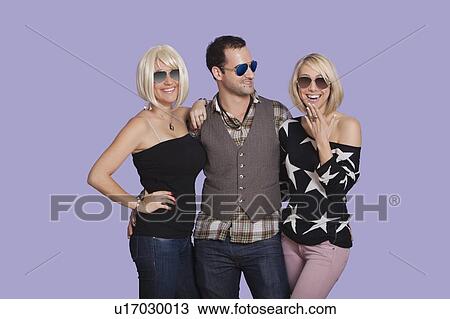 Portrait of young man with two beautiful women over purple background View Large Photo Image Stock Image - Portrait of young man with two beautiful women over purple background. Fotosearch