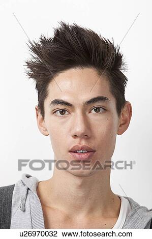 Stock Image - Portrait of young mixed race man with spiked hair against white background. Fotosearch