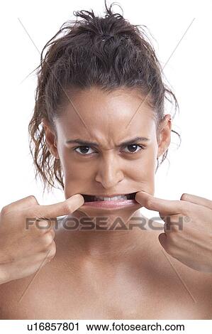 Portrait of young Mixed Race woman pulling her face against white background View Large Photo Image Stock Image - Portrait of young Mixed Race woman pulling her face against white background. Fotosearch