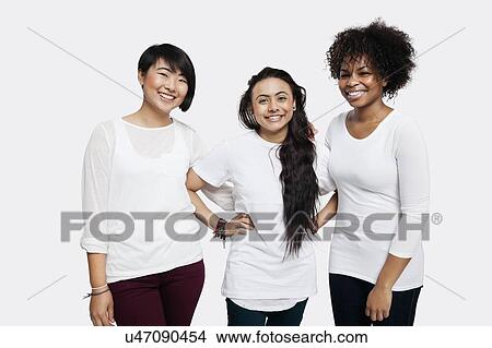 Picture - Portrait of young multi-ethnic female friends in casuals smiling over white background. Fotosearch