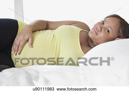 Portrait of young pregnant woman relaxing on bed at home View Large Photo Image Stock Image - Portrait of young pregnant woman relaxing on bed at home. Fotosearch