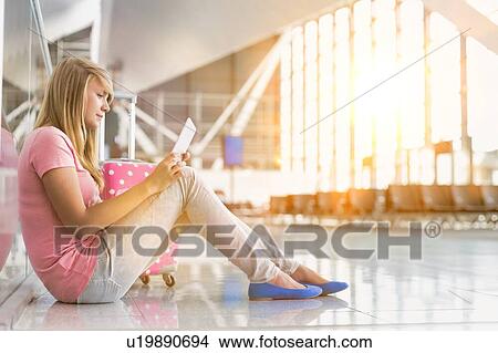 Portrait of young teenage girl sitting on the floor and using digital tablet while waiting for her flight in airport View Large Photo Image Picture - Portrait of young teenage girl sitting on the floor and using digital tablet while waiting for her flight in airport. Fotosearch
