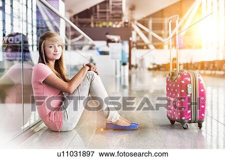 Stock Photo - Portrait of young teenage girl sitting on the floor in airport. Fotosearch