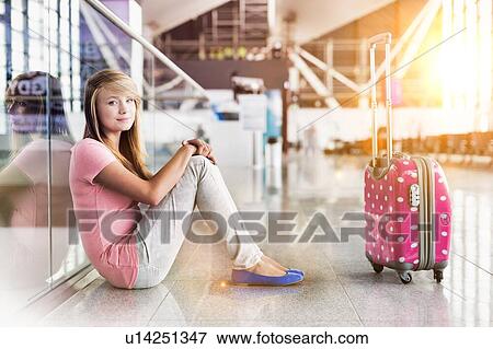 Stock Photo - Portrait of young teenage girl sitting on the floor in airport. Fotosearch