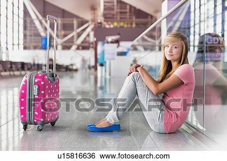 Stock Photograph - Portrait of young teenage girl sitting on the floor in airport. Fotosearch