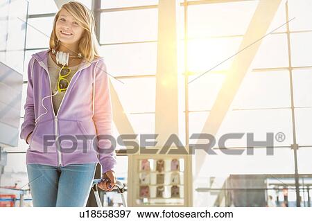 Stock Photo - Portrait of young teenage girl walking with her suitcase in airport. Fotosearch