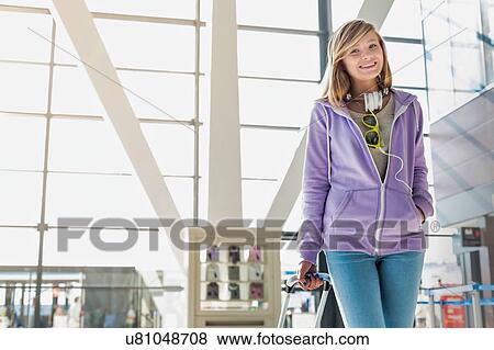Stock Photo - Portrait of young teenage girl walking with her suitcase in airport. Fotosearch