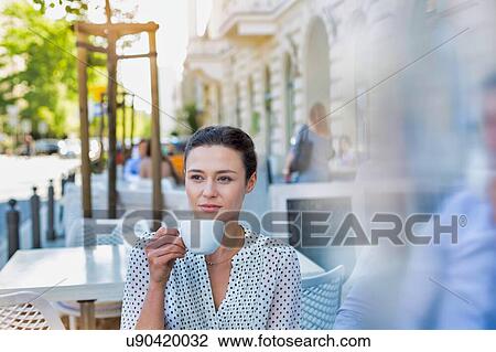 Stock Image - Portrait of young thoughtful and attractive businesswoman sitting while drinking coffee in cafe. Fotosearch