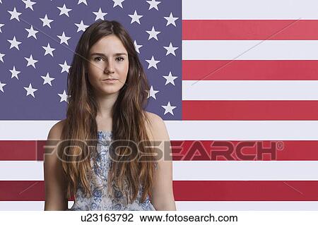 Stock Image - Portrait of young woman against American flag. Fotosearch