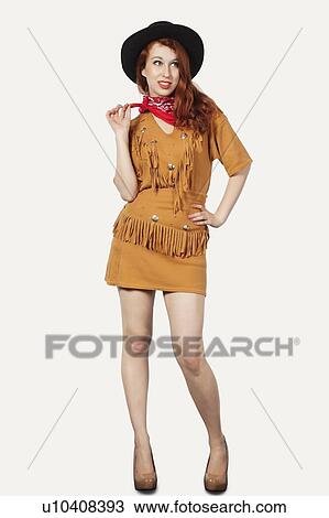 Stock Image - Portrait of young woman dressed as cowgirl against gray background. Fotosearch