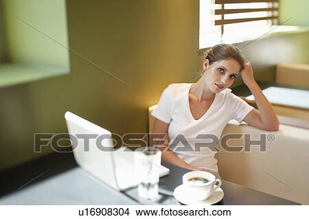 Portrait of young woman sitting at table with laptop in cafe View Large Photo Image Picture - Portrait of young woman sitting at table with laptop in cafe. Fotosearch
