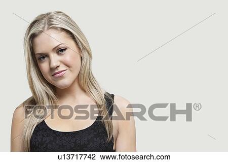 Stock Image - Portrait of young woman smiling over gray background. Fotosearch