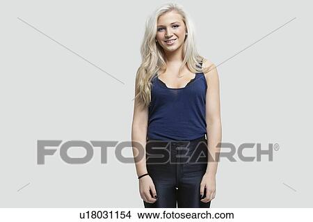 Portrait of young woman standing against gray background View Large Photo Image Picture - Portrait of young woman standing against gray background. Fotosearch